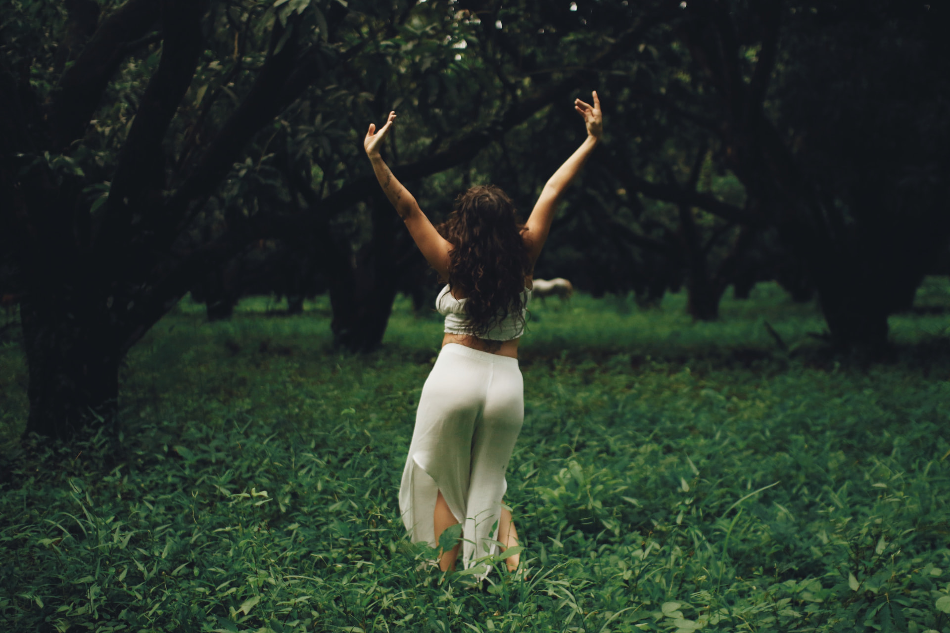 Adelina with her arms raised among trees