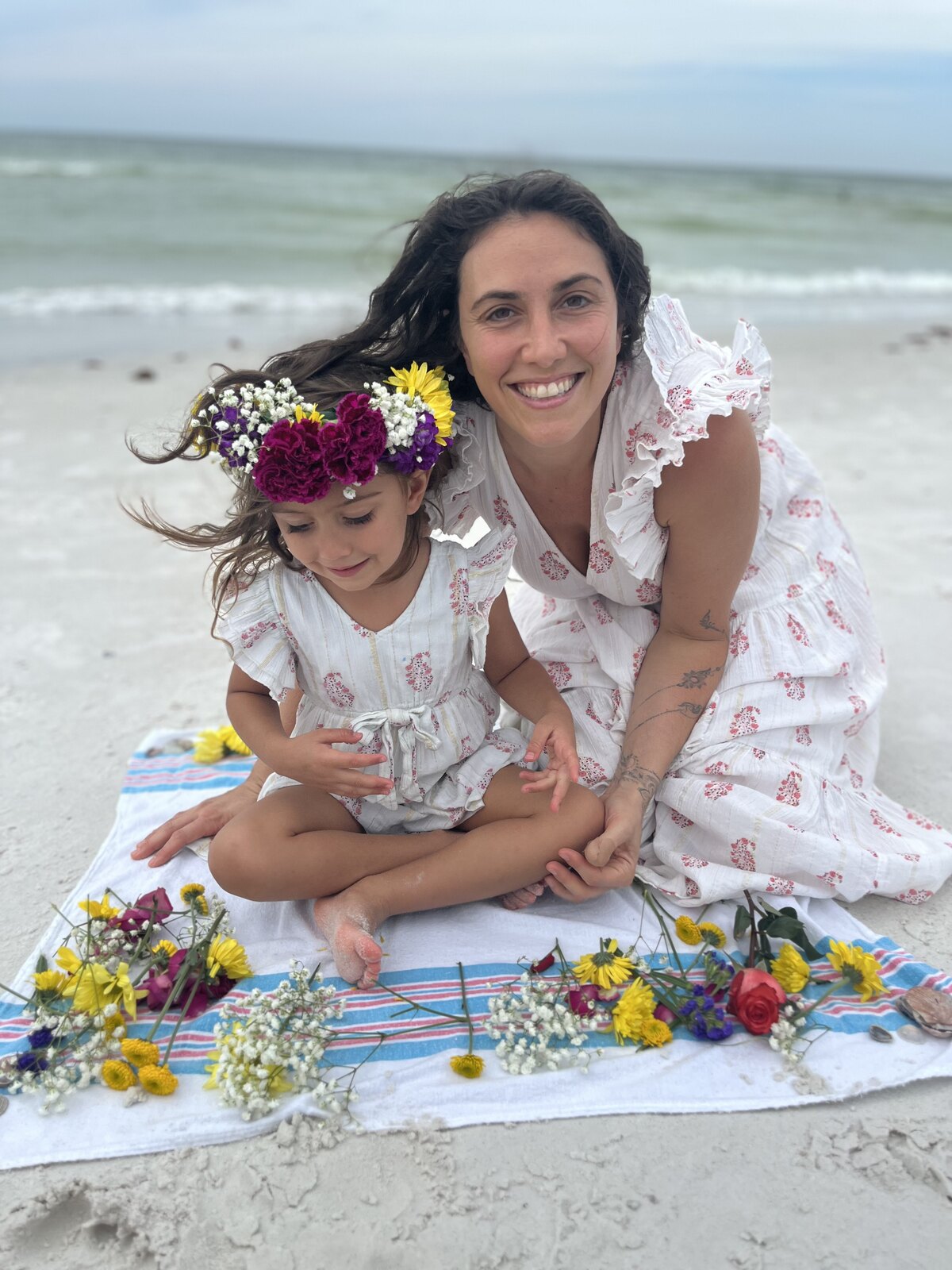 On the beach with my daughter, flowers laid out on a towel between us